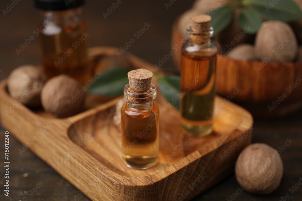Nutmeg essential oil and nuts on wooden table Nutmeg essential oil and nuts on wooden table
