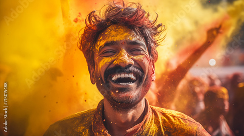 Man with a beaming smile covered with yellow Holi powder with a festive background