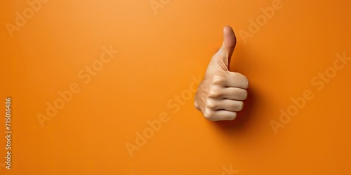 An arm sticks out of an orange wall and shows a thumbs up photo