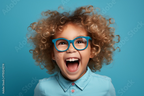 Happy little curly blonde girl isolated on blue background