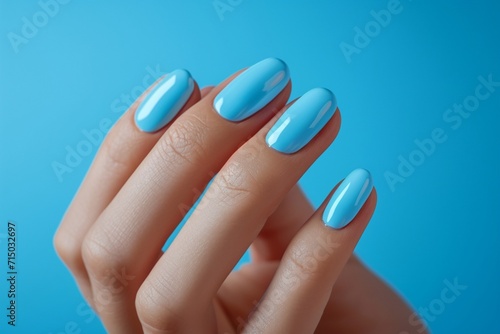 Glamour woman hand with blue nail polish on her fingernails. Pastel color nail manicure with gel polish at luxury beauty salon. Nail art and design. Female hand model. French manicure