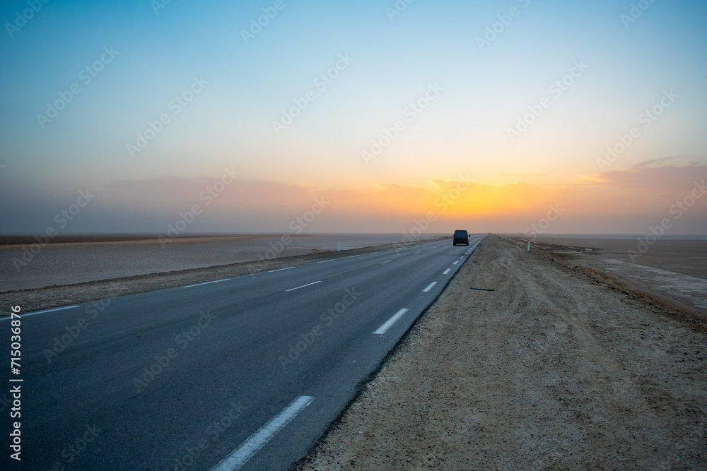 Beautiful colourful sunset over endless empty road in middle of desert. Asphalt highway in Tunisia, North Africa. Beautiful colourful sunset over endless empty road in middle of desert. Asphalt highway in Tunisia, North Africa.