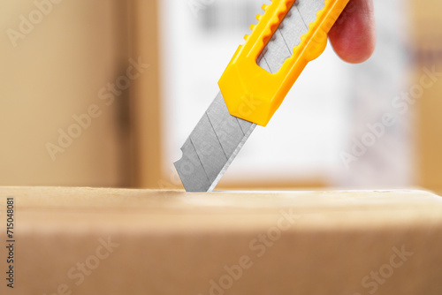 Unboxing cardboard box with utility knife.