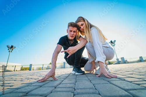 Man Kneeling Next to Woman. A man respectfully lowers himself to the ground as he situates himself beside a woman. photo