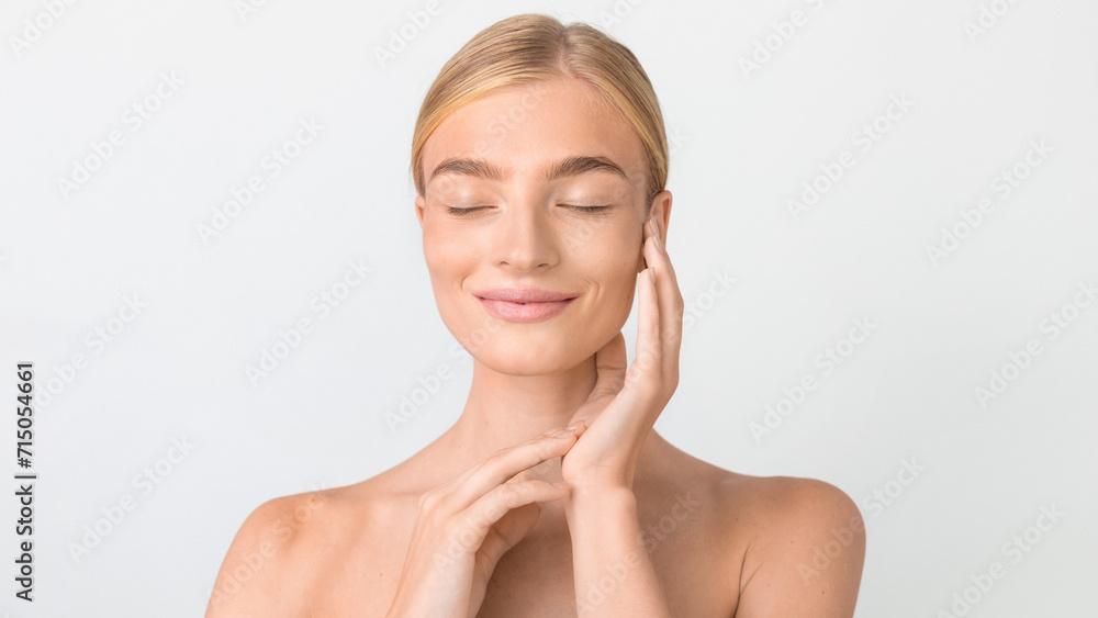 Beauty portrait of blonde lady touching face against white backdrop Beauty portrait of blonde lady touching face against white backdrop