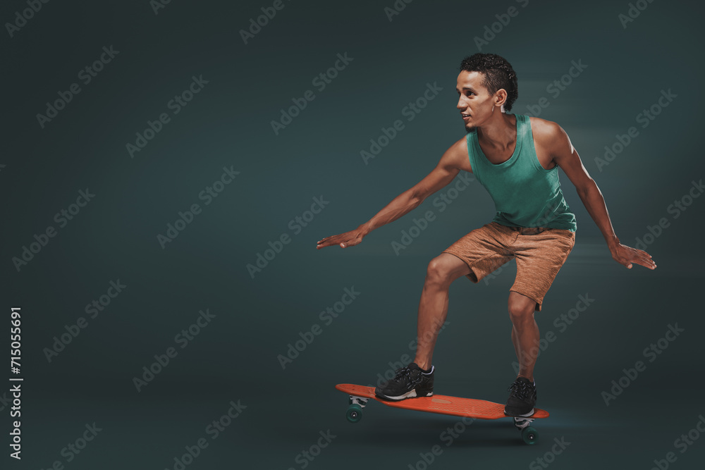 Studio shot of a young man riding a skateboard isolated on dark background