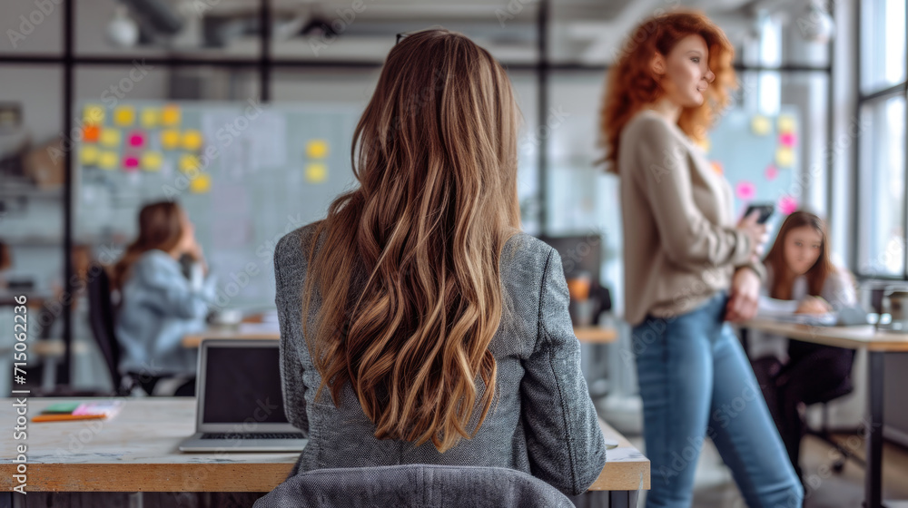 Colleagues in a modern office setting, one from behind, working at a computer. Colleagues in a modern office setting, one from behind, working at a computer.