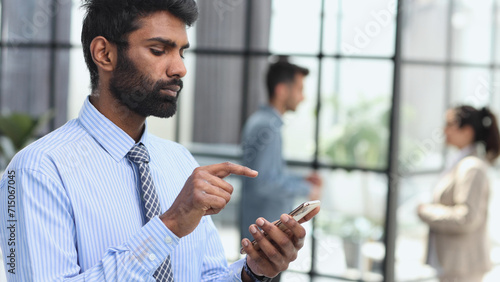 man typing text on smartphone while standing in office