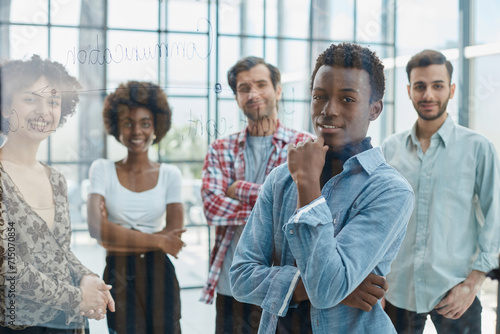 a team of young designers sticking notes on glass in a modern office