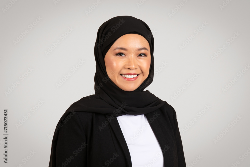 A radiant Asian businesswoman wearing a hijab smiles confidently A radiant Asian businesswoman wearing a hijab smiles confidently