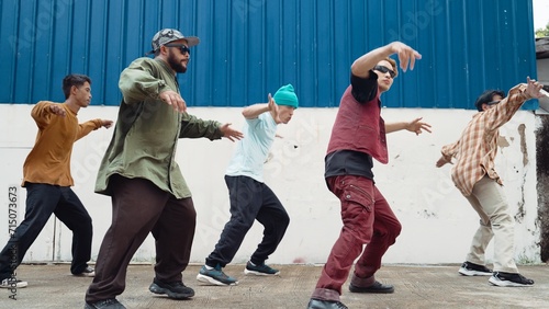 Group of hip hop choreographer dancing street dance together at wall. Young break dancer practicing break dance, moving to modern rhythm, express feeling of lively. Outdoor 2024. Endeavor.