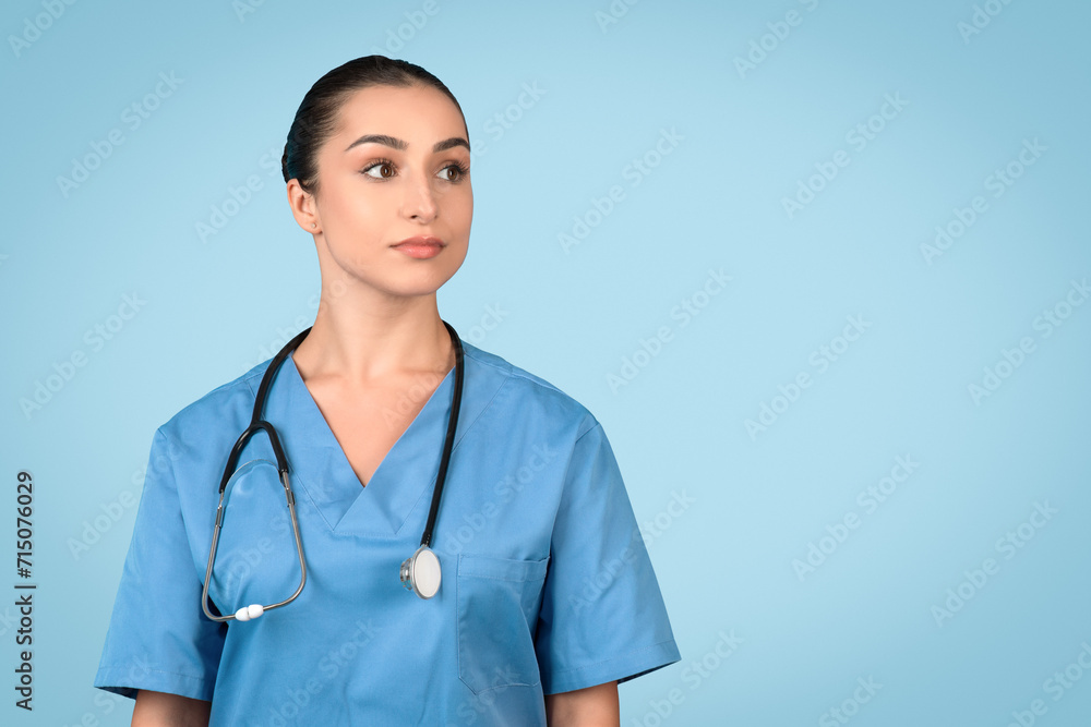 Portrait of european lady nurse posing and looking at free space isolated over blue studio background Portrait of european lady nurse posing and looking at free space isolated over blue studio background