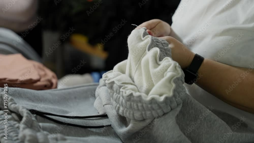 A seamstress cuts threads from ready-made clothes in a sewing factory A seamstress cuts threads from ready-made clothes in a sewing factory