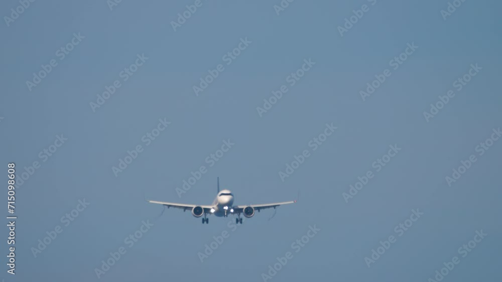 Passenger plane with unrecognizable livery approaching landing, long shot. Jet aircraft in the sky, front view Passenger plane with unrecognizable livery approaching landing, long shot. Jet aircraft in the sky, front view