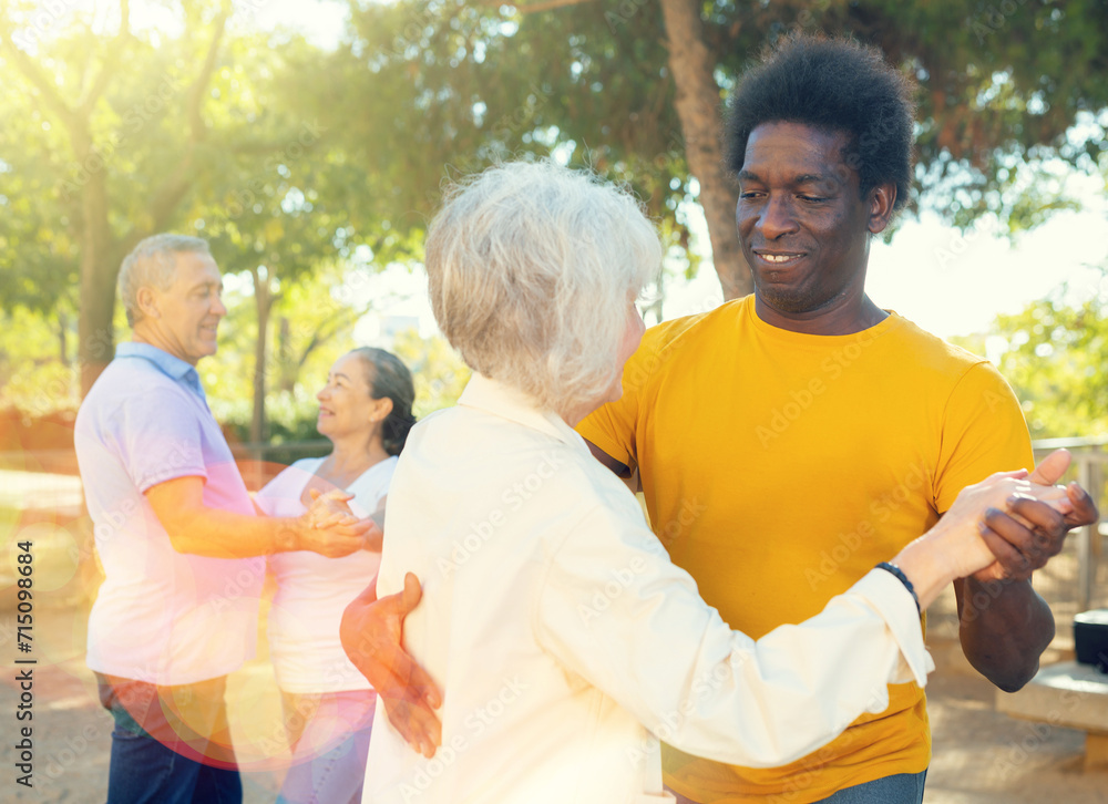 Obraz premium Smiling elderly woman enjoying dance with partner in garden
