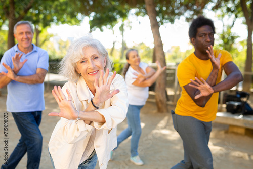 Group of happy women and men different ages practicing dance in a summer park