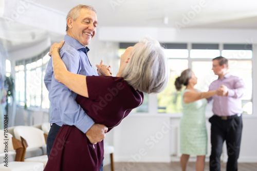 Aged couple in their free time engaged in latin dance class and learns movements of cha-cha-cha dance photo