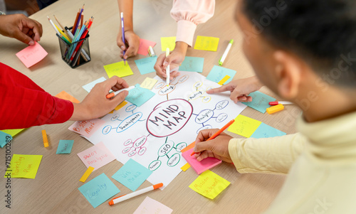 Professional startup group share creative marketing idea by using mind map. Young skilled business people brainstorm business plan while writing sticky notes. Focus on hand. Closeup. Variegated.