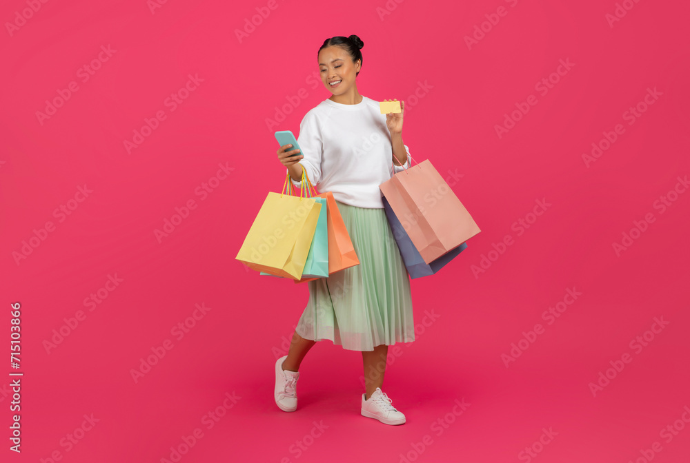 Happy asian shopaholic lady shopping online with smartphone and credit card