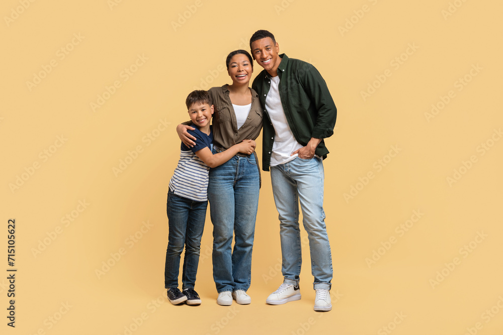 Portrait of happy african american family embracing on beige background Portrait of happy african american family embracing on beige background