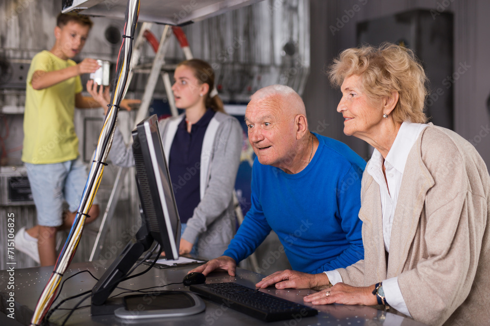 Senior man and woman using computer to solve conundrum in escape room 
