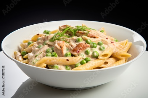  a bowl of pasta with peas and chicken in a creamy sauce on a white tablecloth with a black background.