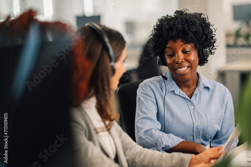 African american woman with headset working and talking with colleague