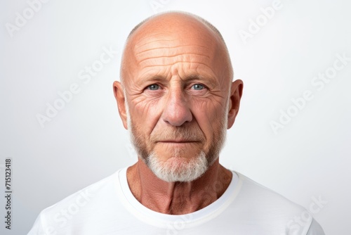Portrait of a senior man looking at the camera while standing against white background