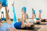 Motivated sporty woman exercising during group training with bender ball at gym. Healthy lifestyle and pilates concept