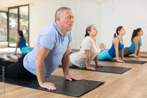 People of different ages performing cobra exercise during group Pilates workout. Active lifestyle and wellness concept