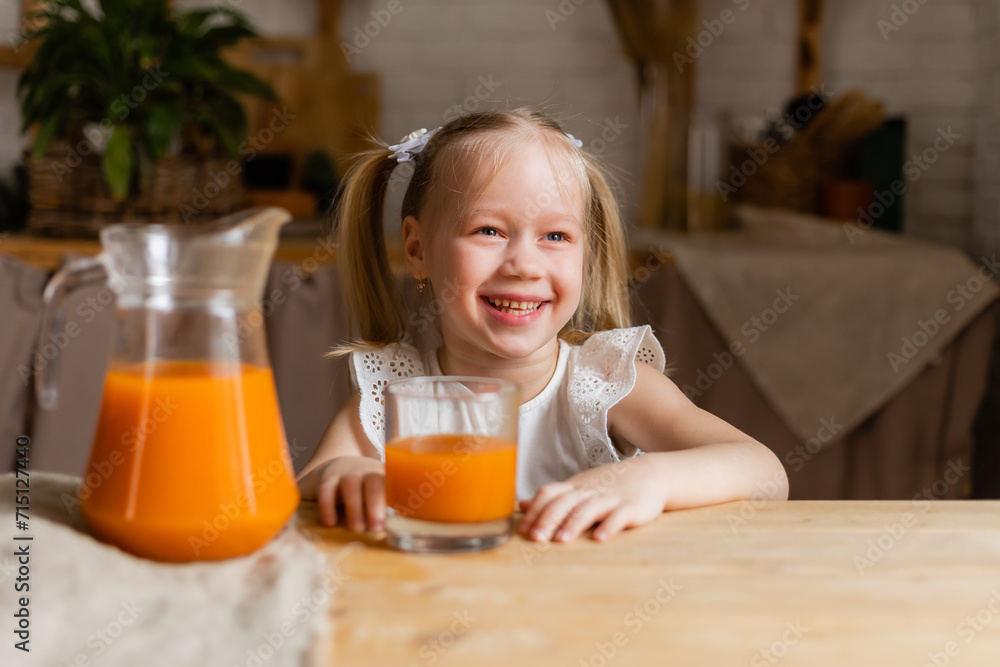 Cute little blonde girl drinking fresh orange juice in the kitchen Cute little blonde girl drinking fresh orange juice in the kitchen