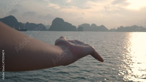 Detail of a hand moving with Halong Bay on the horizon during a sunset. Holidays in Veitnam photo