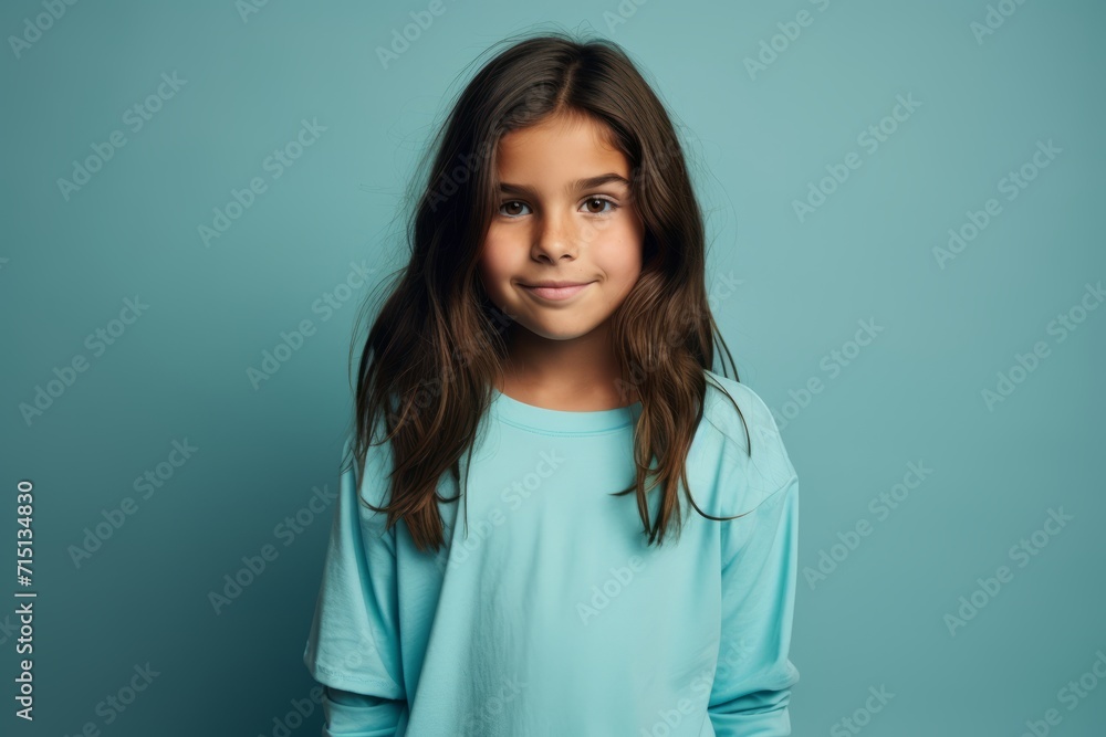 Portrait of a pretty little girl looking at camera and smiling while standing against blue background Portrait of a pretty little girl looking at camera and smiling while standing against blue background