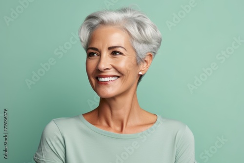 Portrait of smiling senior woman with grey hair over turquoise background