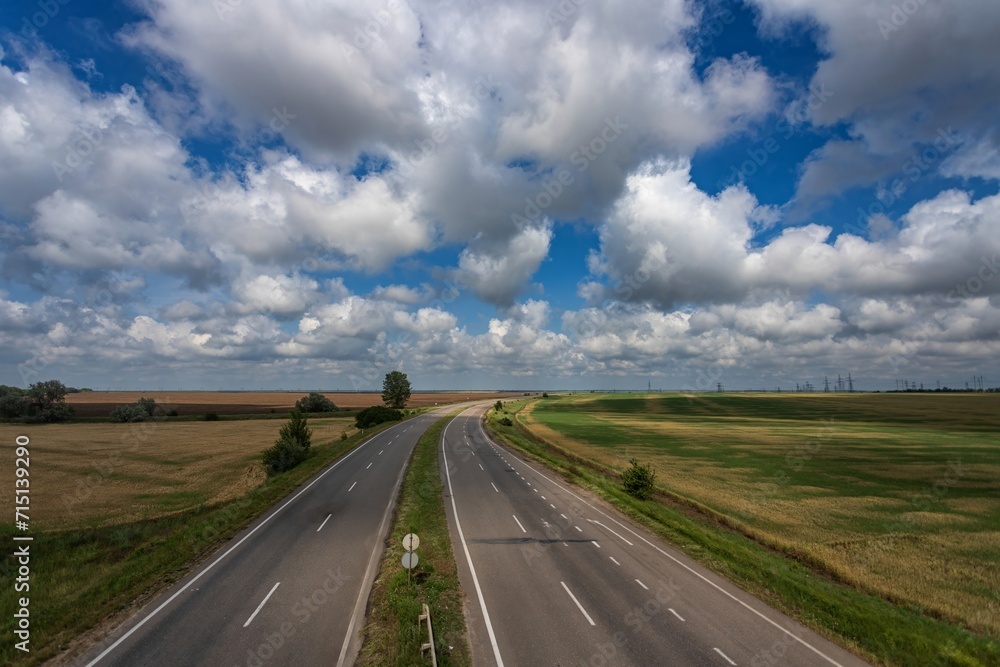 Highway among fields under a beautiful sky with white clouds