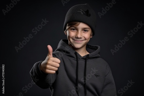 teenage boy in a black hoodie and hat showing thumbs up