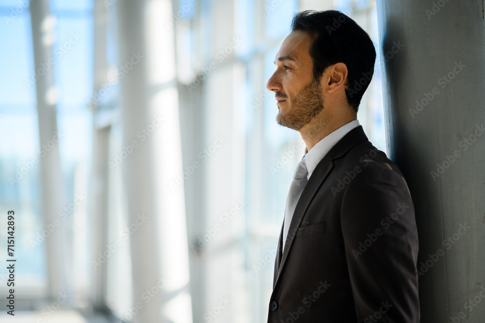 Confident businessman gazing through office windows Confident businessman gazing through office windows