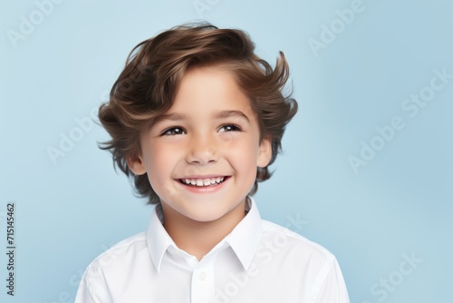smiling little boy in white shirt and hairstyle over blue background