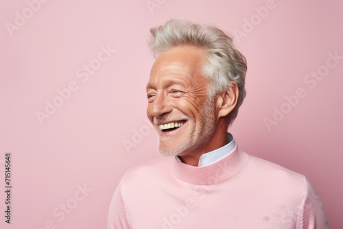 Portrait of a smiling senior man in pink sweater on pink background