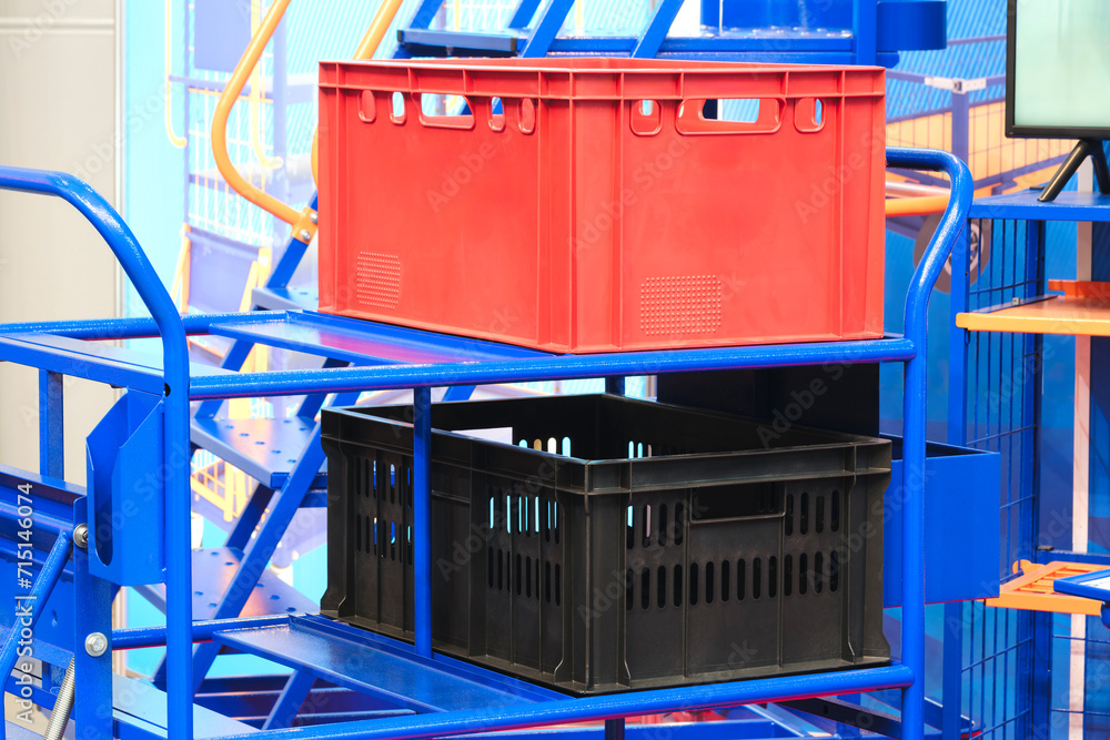 Multicolored plastic boxes on a metal cart in a modern warehouse, logistics concept background