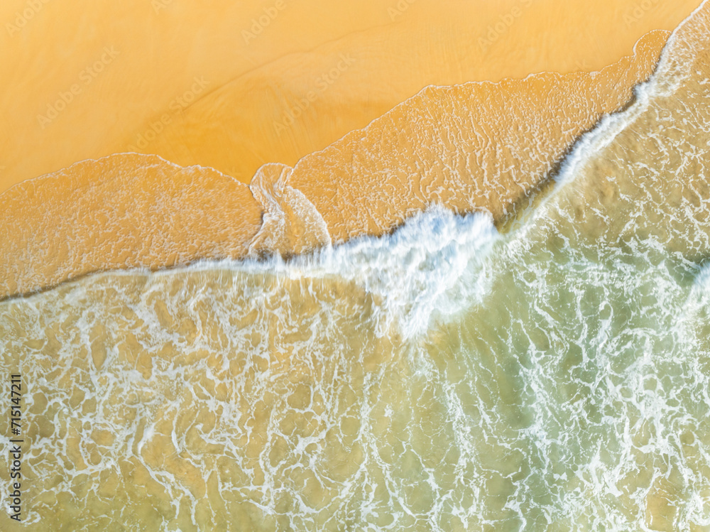 Top view beach with waves crashing on sandy shore,Beautiful waves sea surface in summer seascape background,Amazing beach colorful water background Top view beach with waves crashing on sandy shore,Beautiful waves sea surface in summer seascape background,Amazing beach colorful water background