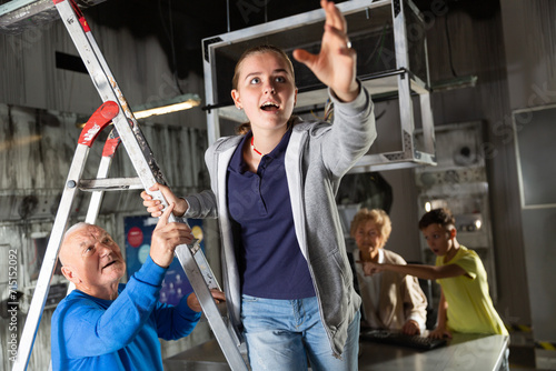 Focused girl pointing to something while trying to find solution of conundrum with relatives in quest room