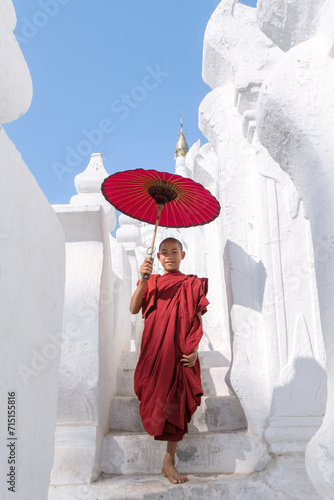 Young novice monk walking on white pagoda, Myanmar photo