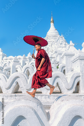 Young novice monk jumping on white pagoda, Myanmar photo