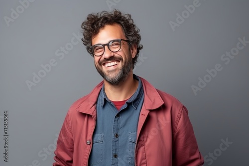 Portrait of a handsome young man with curly hair and glasses against grey background