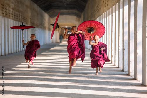 Novice monks with umbrellas running at temple, Bagan, Myanmar photo