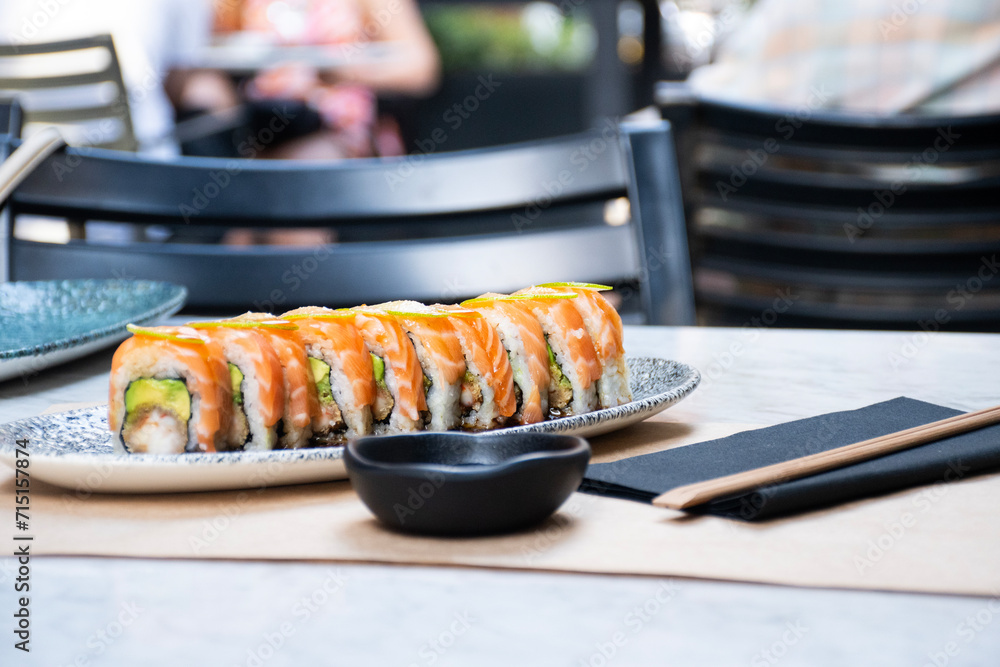 Φωτογραφία sushi maki roll of salmon avocado and cut shrimp and chopsticks in front of blur