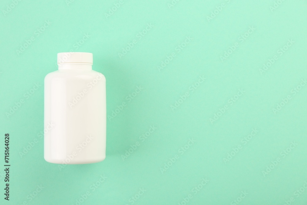 Blank white pill bottle on turquoise background, top view. Space for text Blank white pill bottle on turquoise background, top view. Space for text