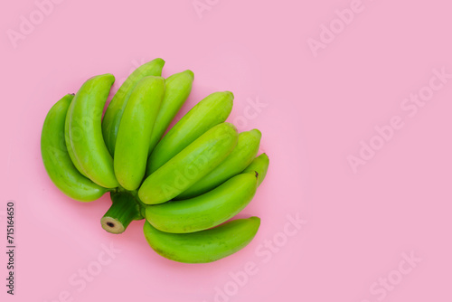 Green banana on pink background. © Bowonpat