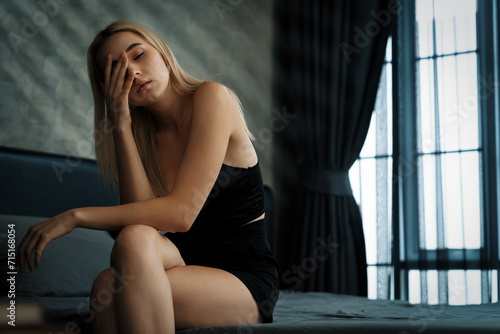 Young woman with critical depression and anxiety disorder from loneliness, mental sickness, or unwanted pregnancy, cuddling herself on dark bedroom. Overwhelming negative thought. Blithe